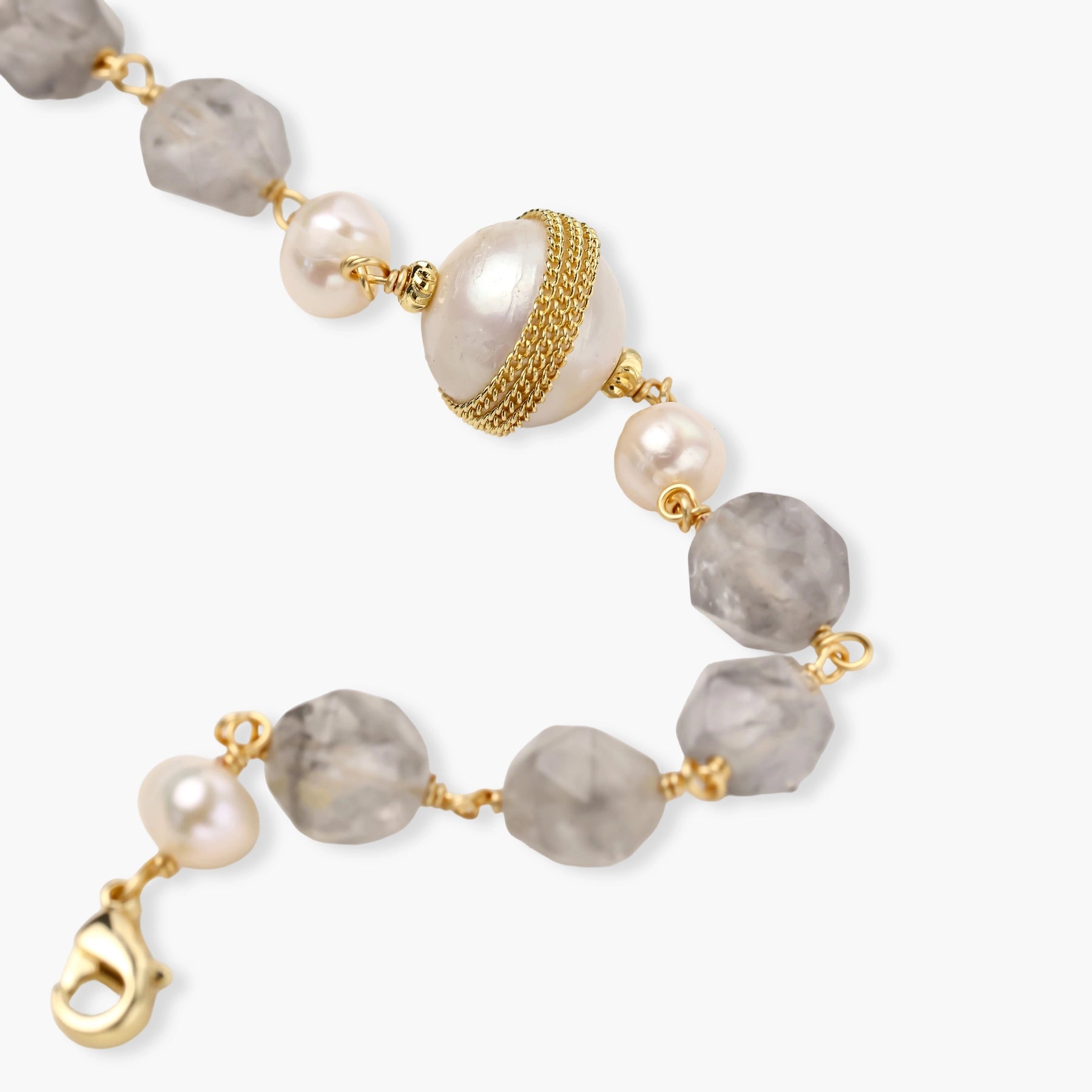 Bracelet with cloudy quartz beads, freshwater pearls, and gold-wrapped baroque pearl centerpiece on white background.
