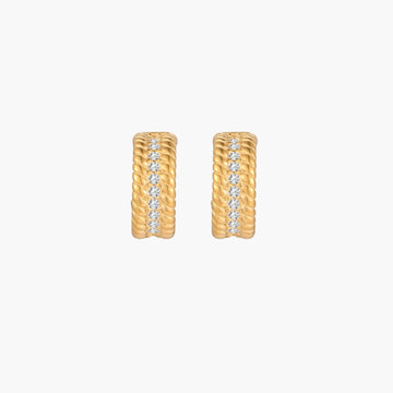 Textured gold huggie hoop earrings with raised ribbed rows creating dimensional sculptural design on cream background